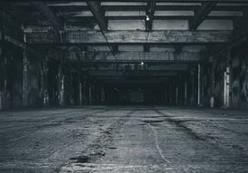 Тъмно пусто складово помещение с бетонни колони и светлина