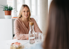 Žena sediaca pri stole s fľašou vody