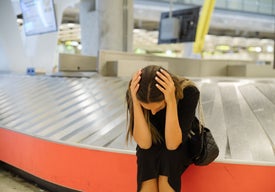 Отчаяна жена седи на празна багажна лента на летище - явно е със загубен багаж и без покритие за това към застраховката си 