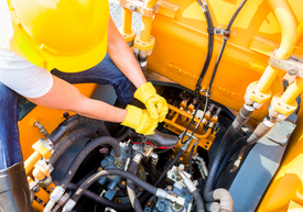 Kesztyűt és kesztyűt viselő személy egy sárga gépen