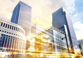 Високи бизнес сгради с размазани нощни светлини на преден план.