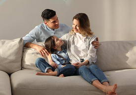 Egy férfi és egy nő ül egy kanapén egy lánnyal