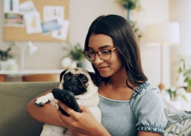 Žena drží psa a dívá se na telefon