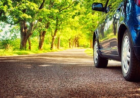 Auto jedoucí po silnici okolo jarních stromů 