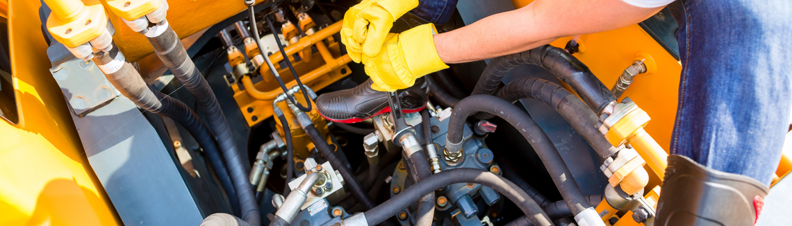 Egy sárga kesztyűt viselő személy, kezében egy csavarkulccsal.