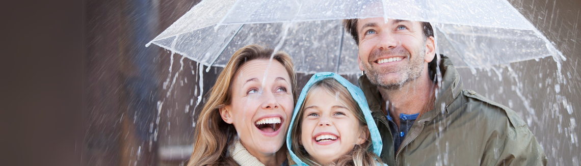 uśmiechnięci rodzice z córką pod parasolem podczas deszczu