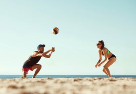 Muž a žena hrající volejbal na pláži
