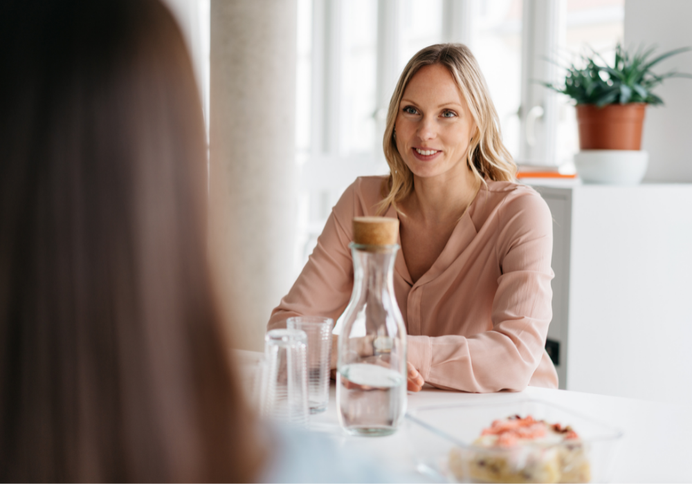 Žena sediaca pri stole s fľašou vody