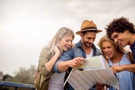 Двама млади мъже и две жени гледат усмихнати пътна карта, явно търсят пътя.