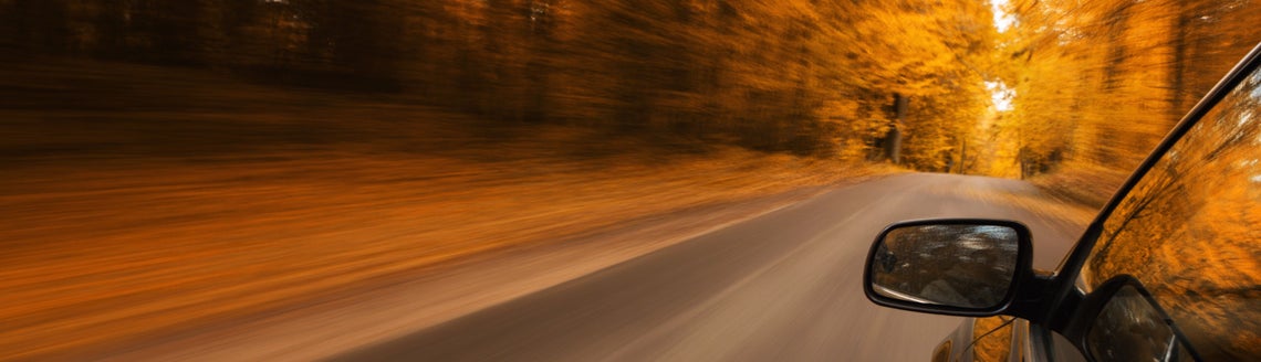 Rozmazaná silnice s podzimními stromy v pozadí