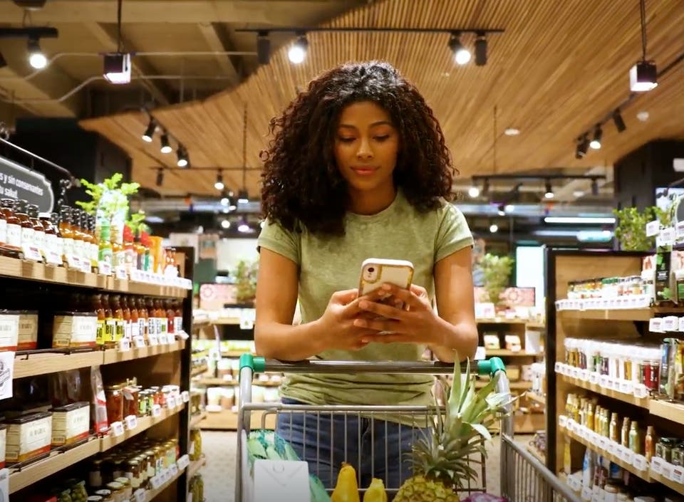 Frau mit Smartphone im Supermarkt