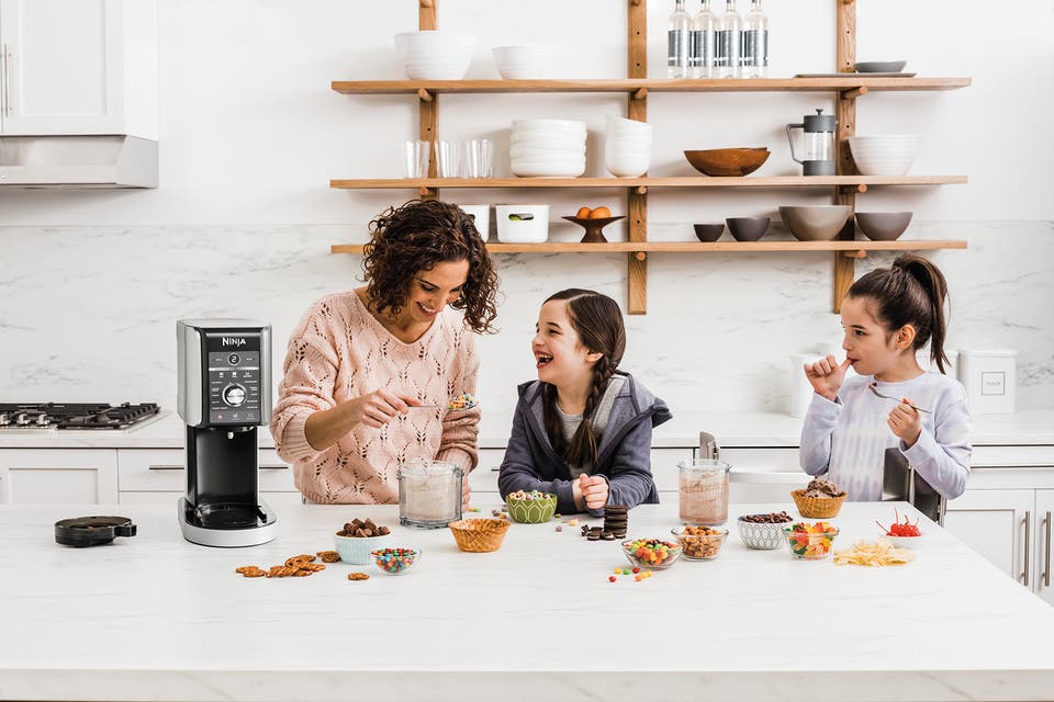 Woman and girls using Ninja Creami ice maker in their kitchen