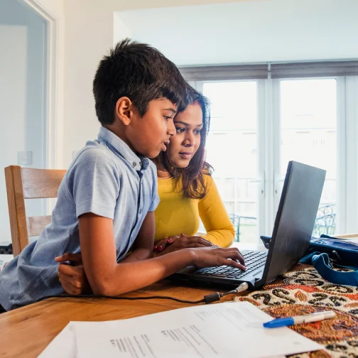 Woman and child doing homework  on a laptop