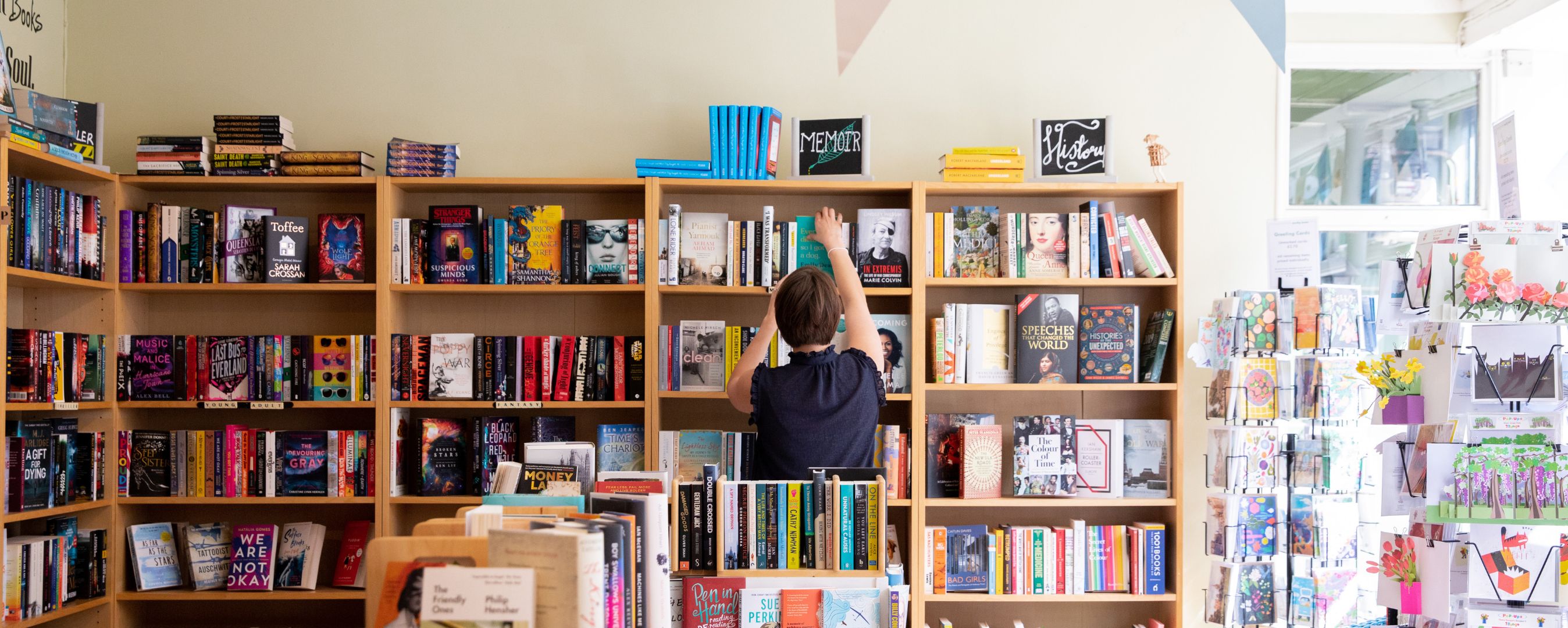 person putting book on shelf 