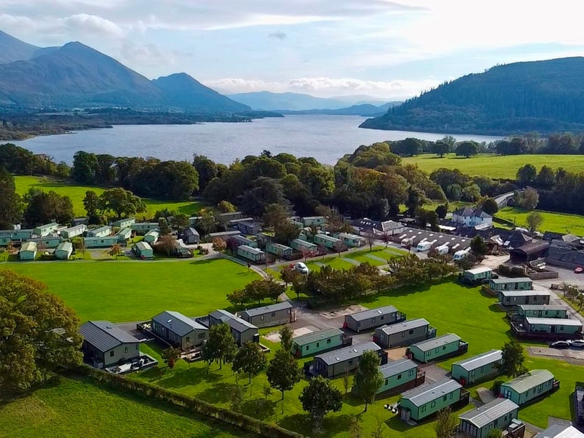 Ariel shot of a holiday park by a river side and mountains.