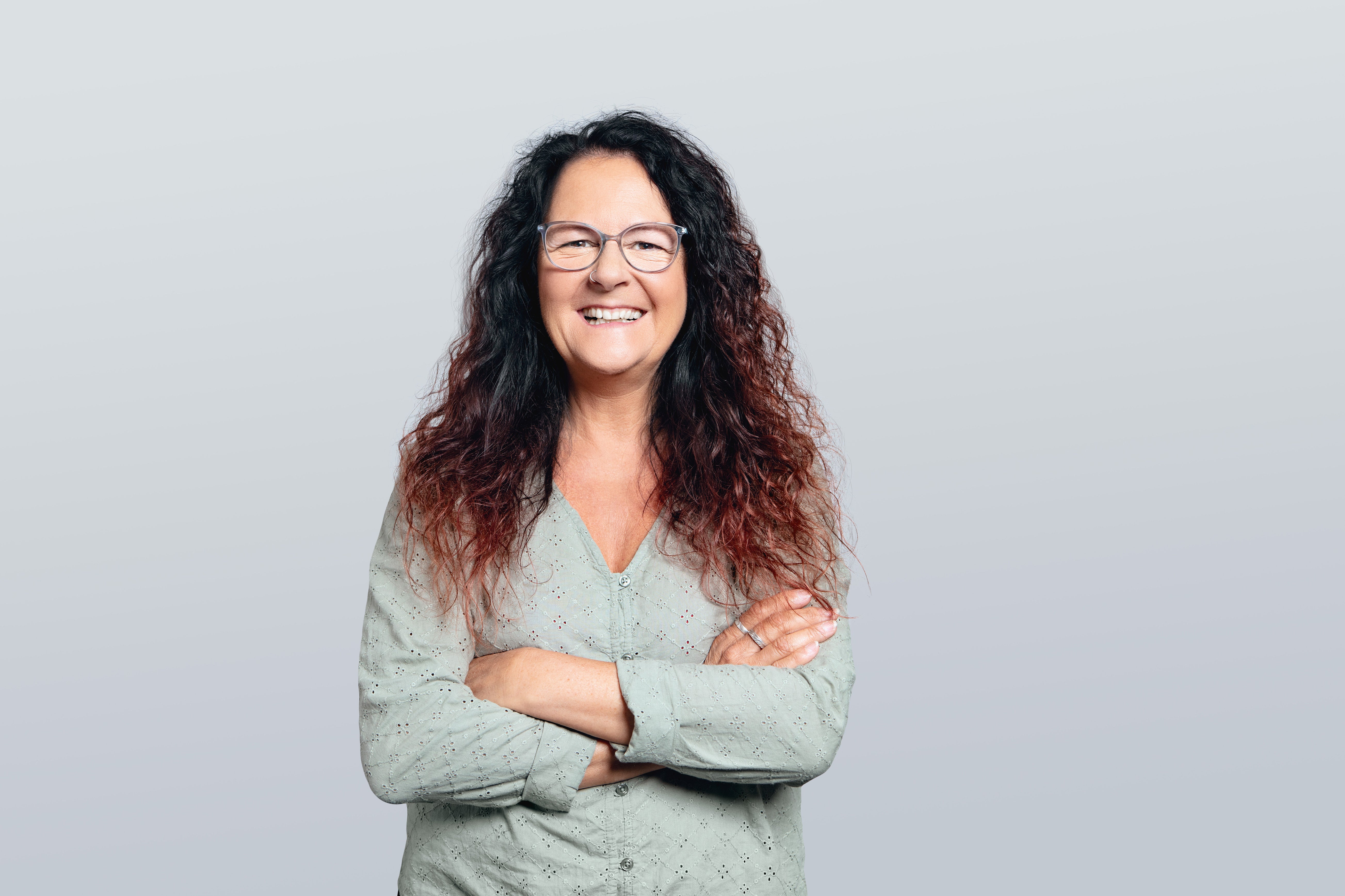 Frau mit langen lockigen Haaren lächelt in die Kamera