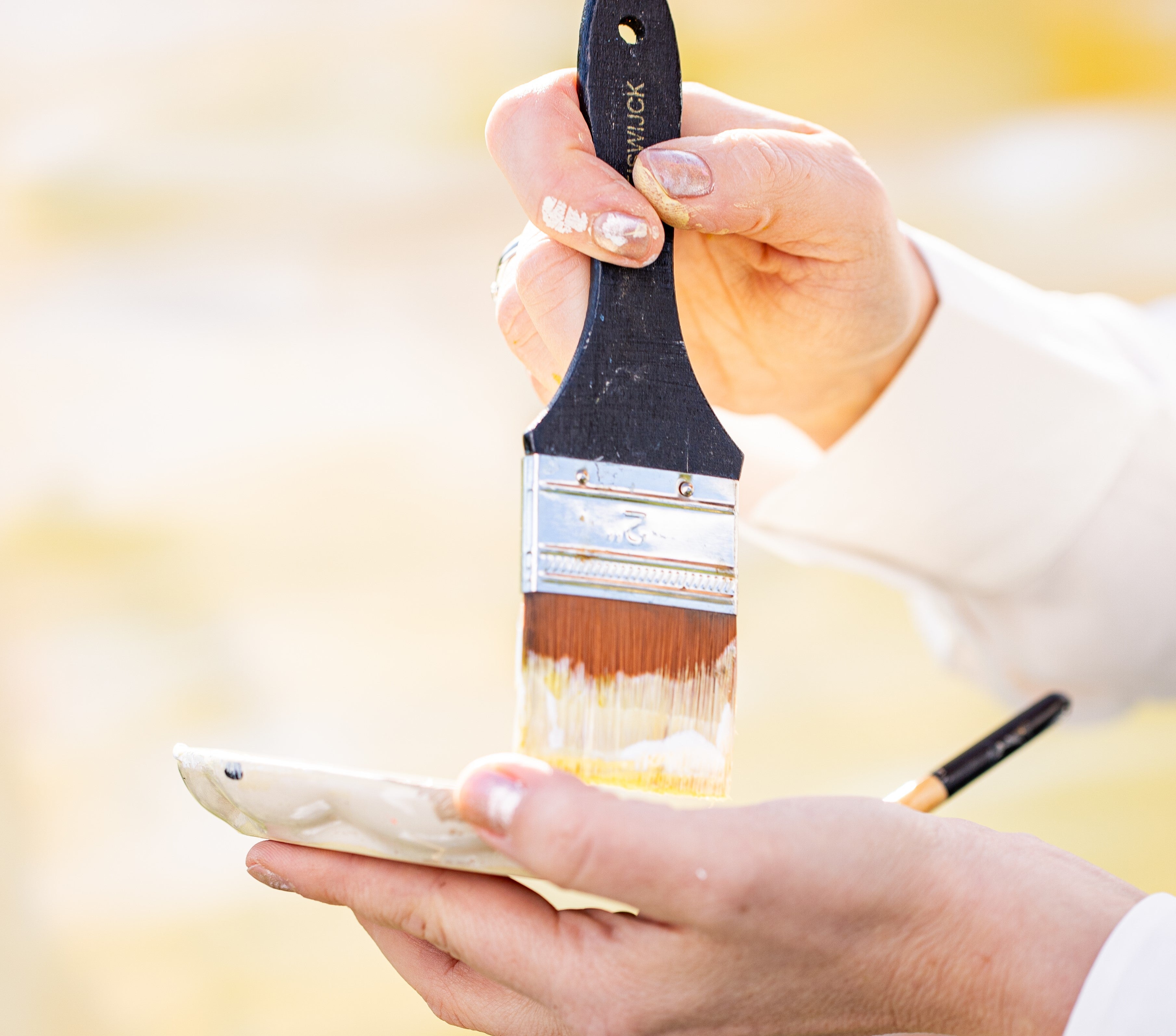 Eine Person hält einen Pinsel über eine Farbpalette.