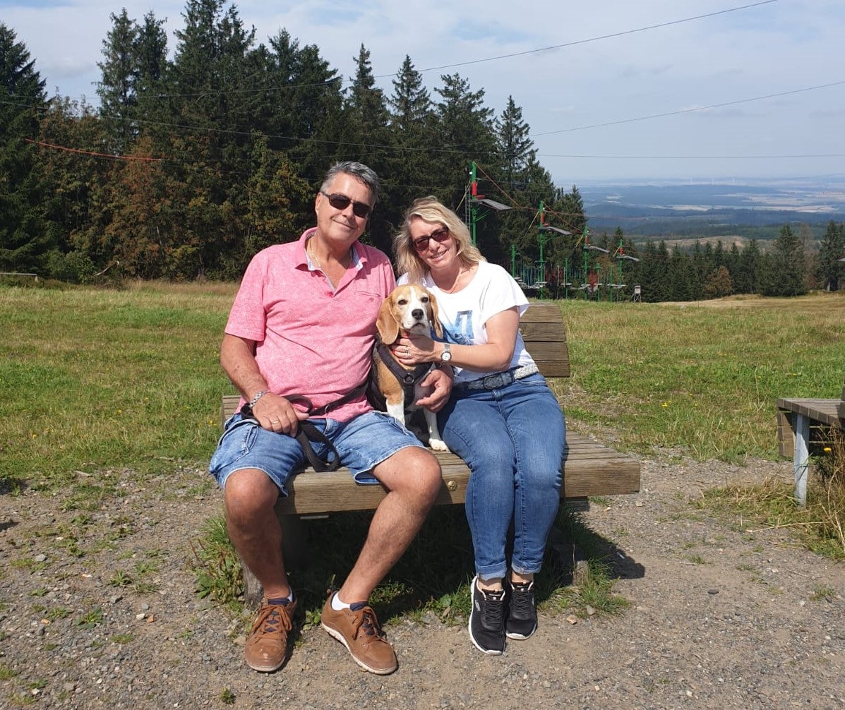 Frank und seine Frau sitzen auf einer Bank mit ihrem Hund.