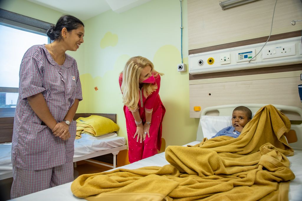 Eine Frau steht neben einem Jungen in einem Krankenhausbett