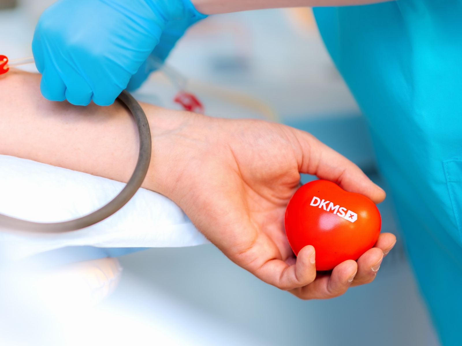 Eine Hand hält ein DKMS Herz während der Stammzellentnahme