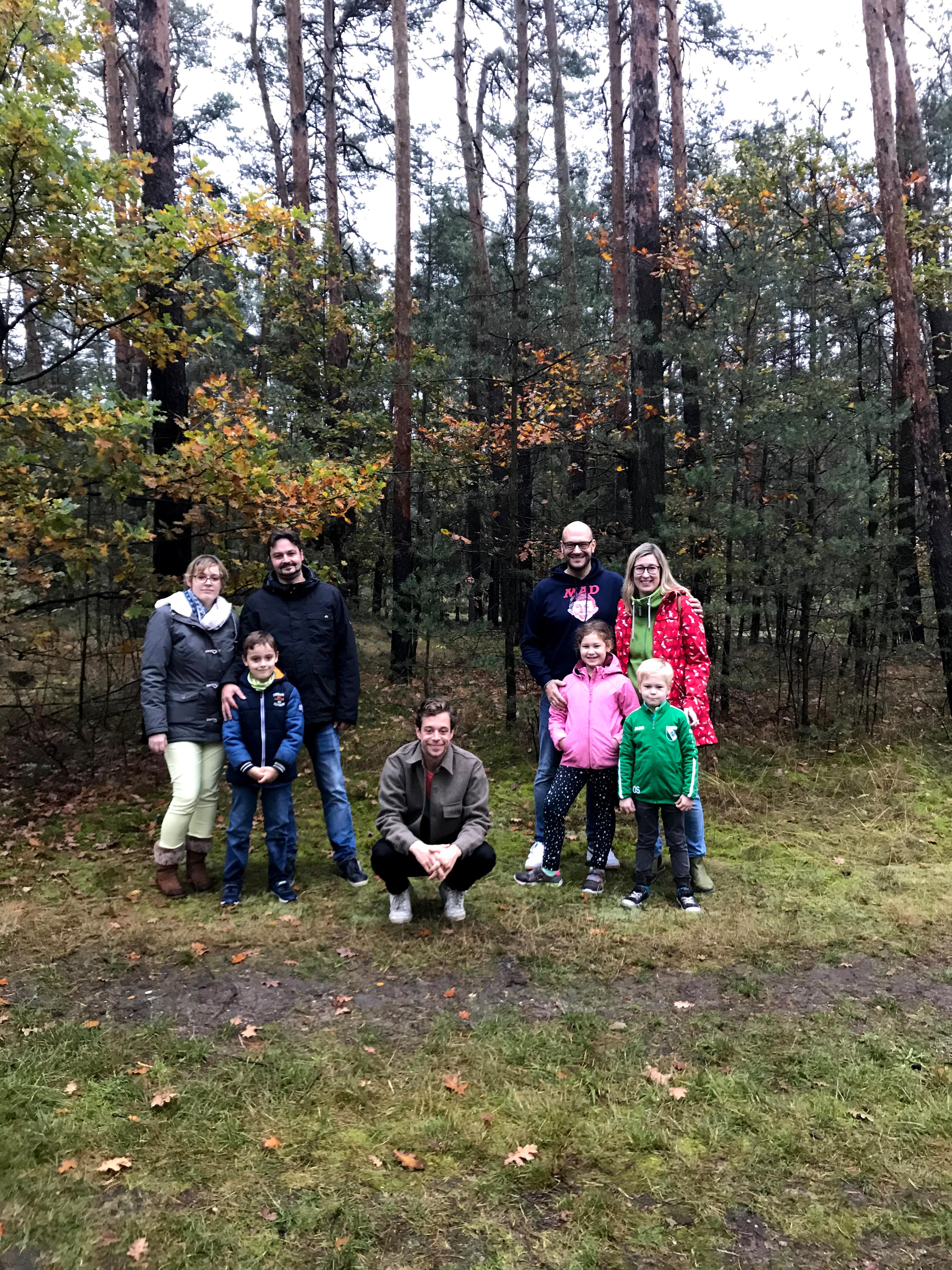 Checker Tobi mit beiden Familien, sie posieren vor einem Wald