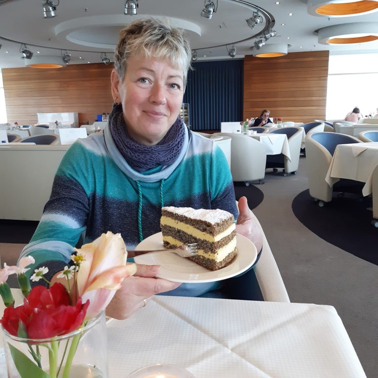 Eine Frau hält einen Teller mit einem Kuchen und lächelt.