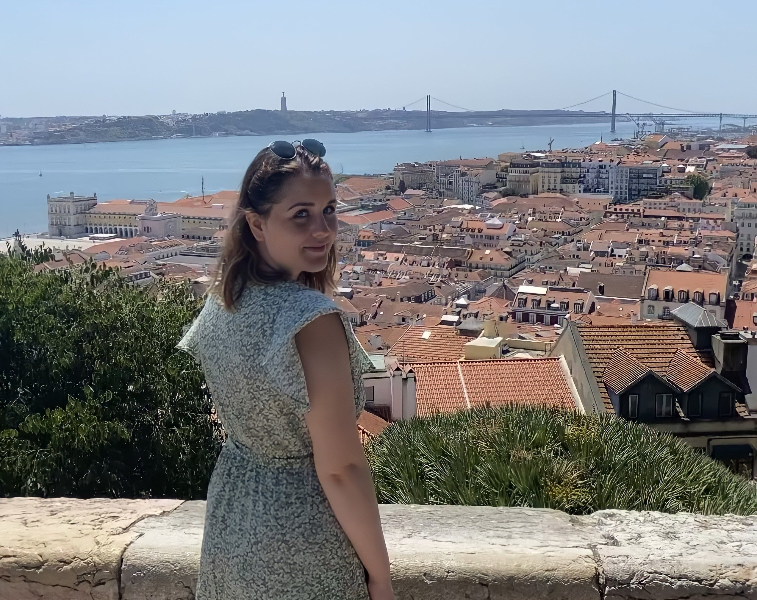 Eine Frau steht auf einem Felsvorsprung mit Blick auf eine Stadt