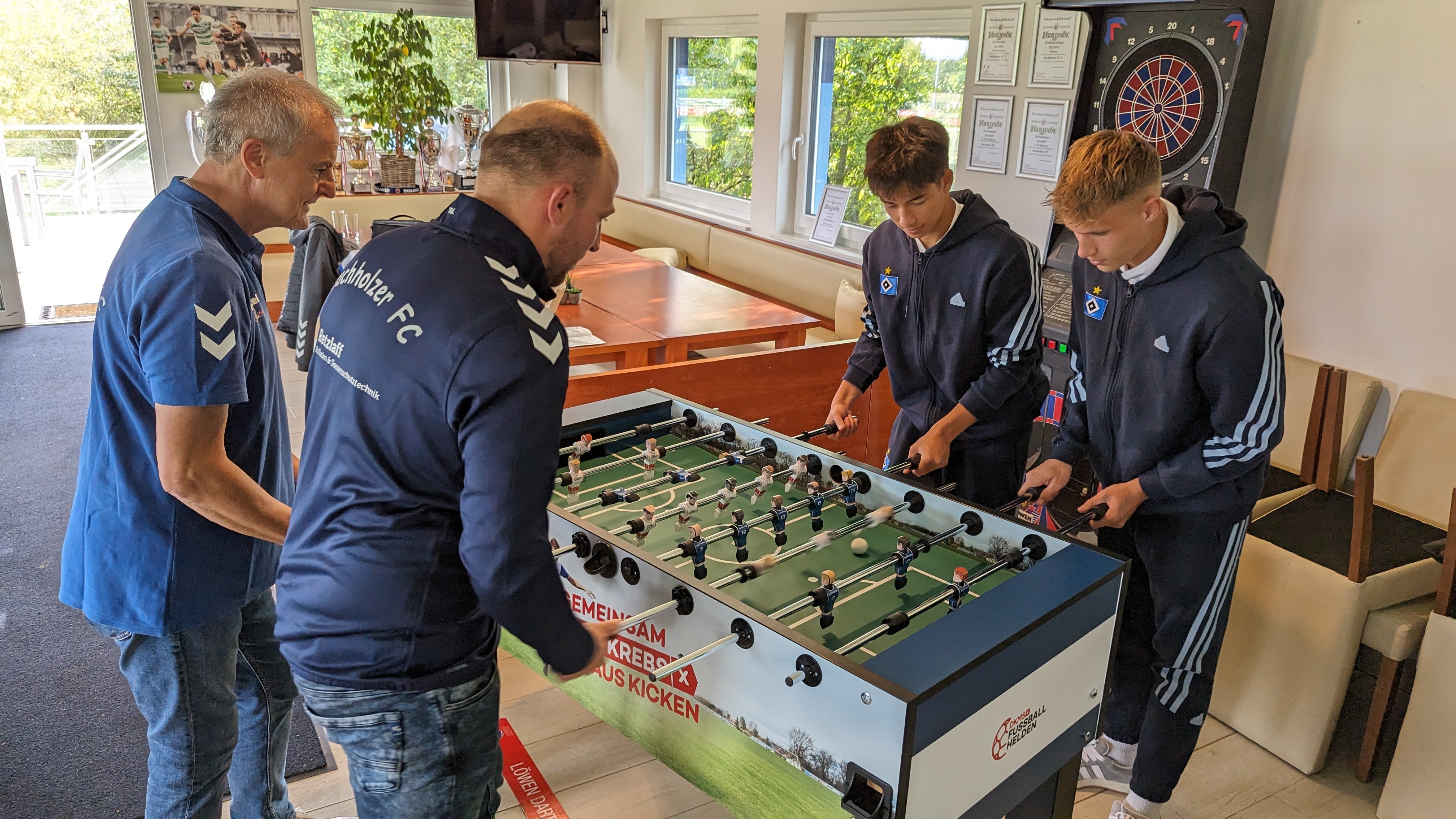 Vier Männer spielen zusammen Kicker 