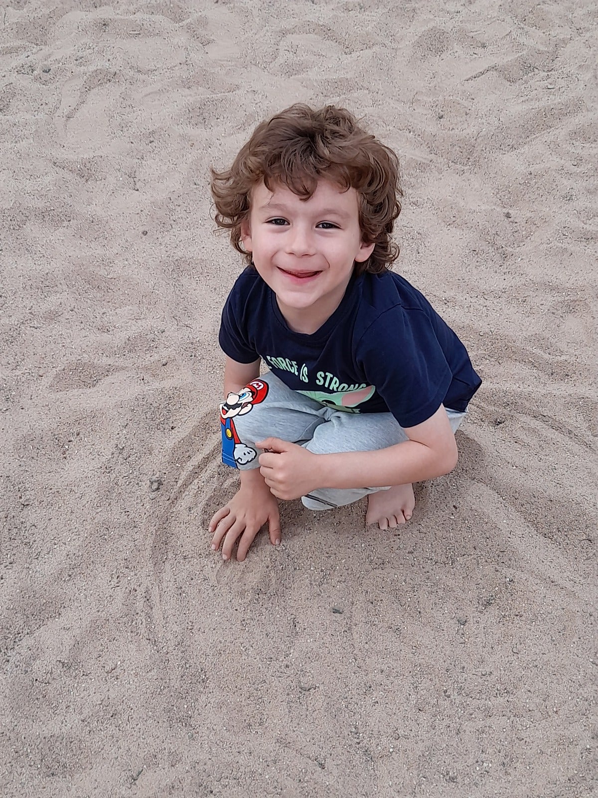 ein Kind hockt im Sand