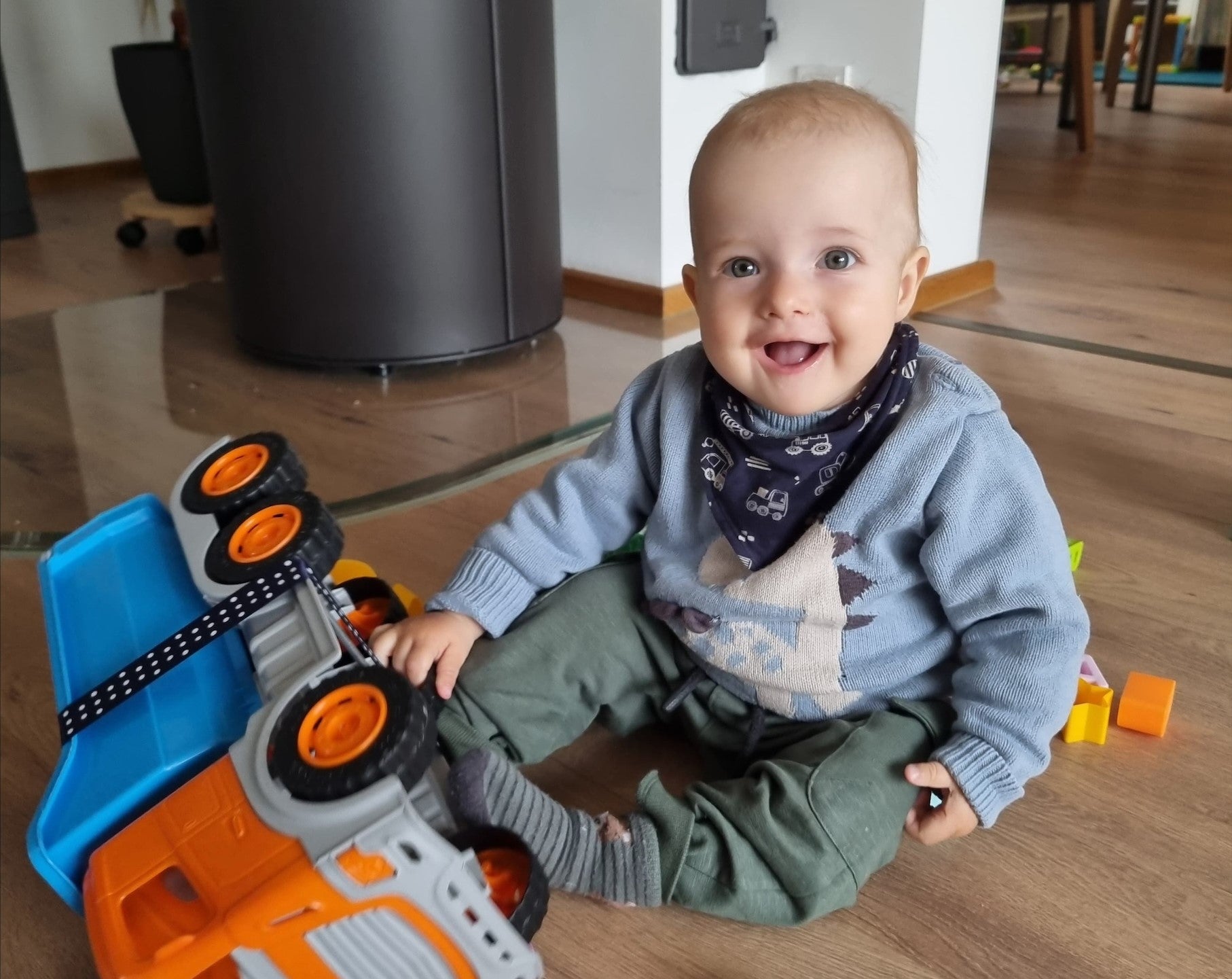 Ein Baby sitzt auf dem Boden und spielt mit einem Spielzeug-LKW