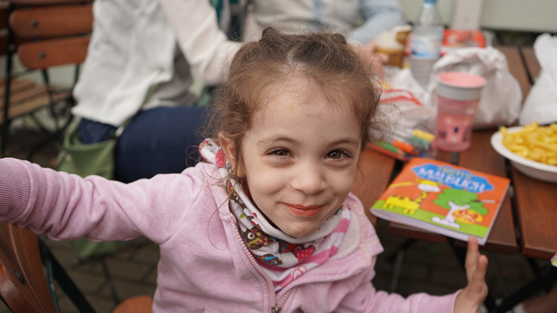 Mädchen mit pinken Pulli lächelt in die Kamera