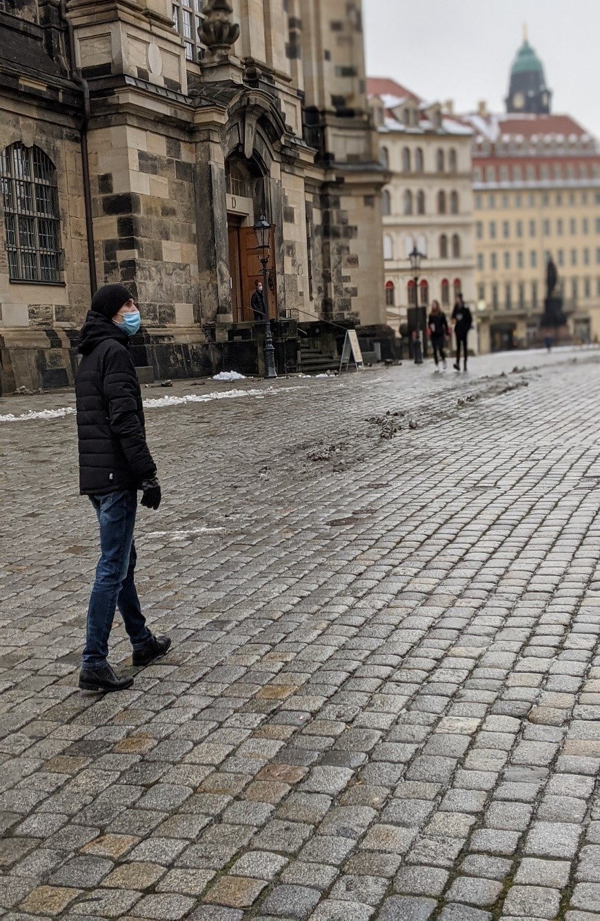 Sebastian trägt einen Mundschutz, und läuft über eine Kopfsteinpflasterstraße 