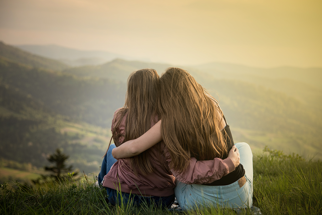 Zwei Frauen sitzen auf einem Hügel mit Blick auf die Berge