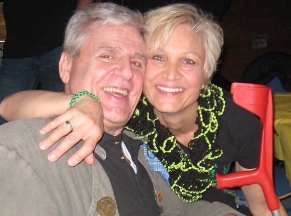 ein Mann und eine Frau sind Arm in Arm und lachen in die Kamera