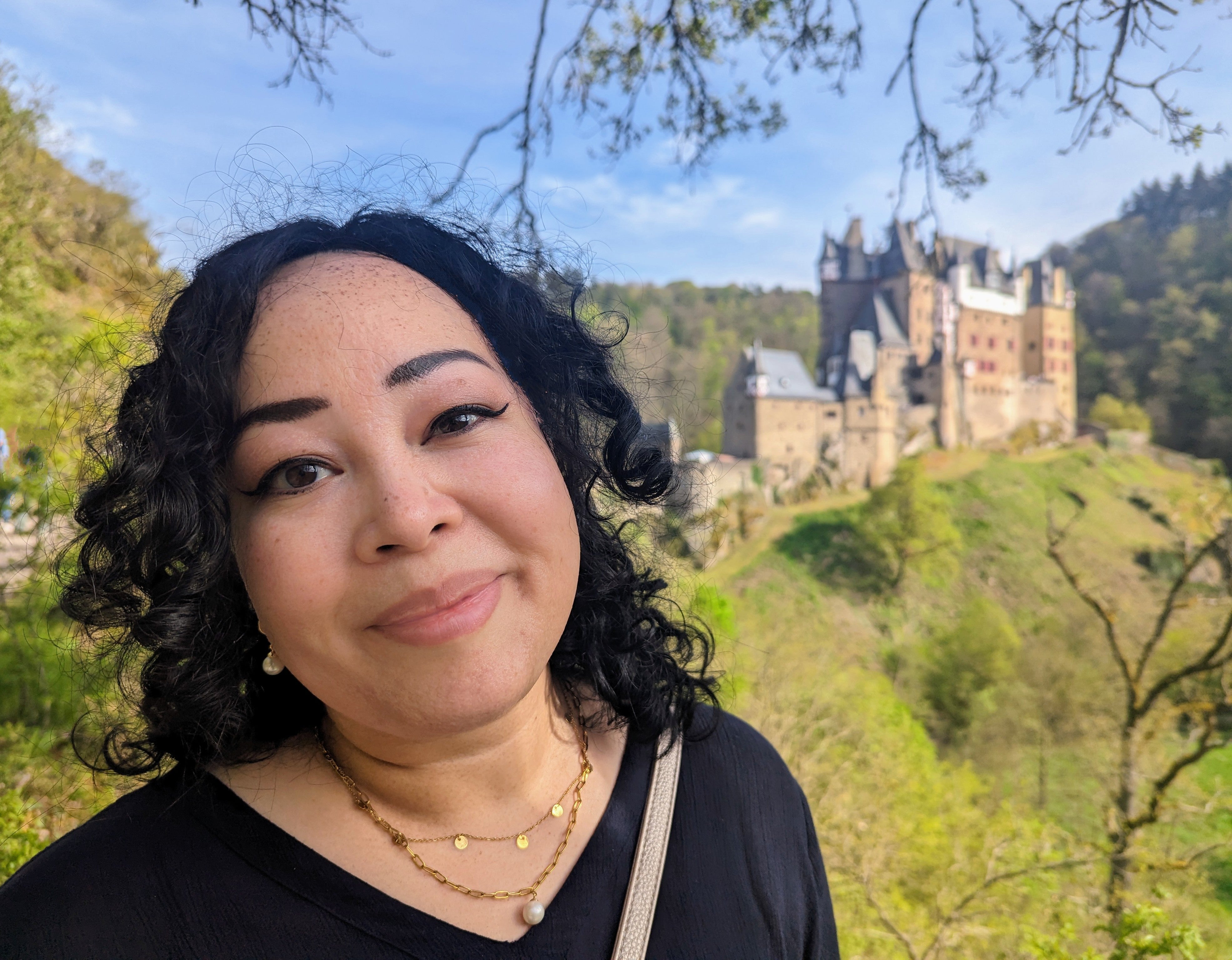 Eine Frau macht ein Selfie mit einer Burg im Hintergrund