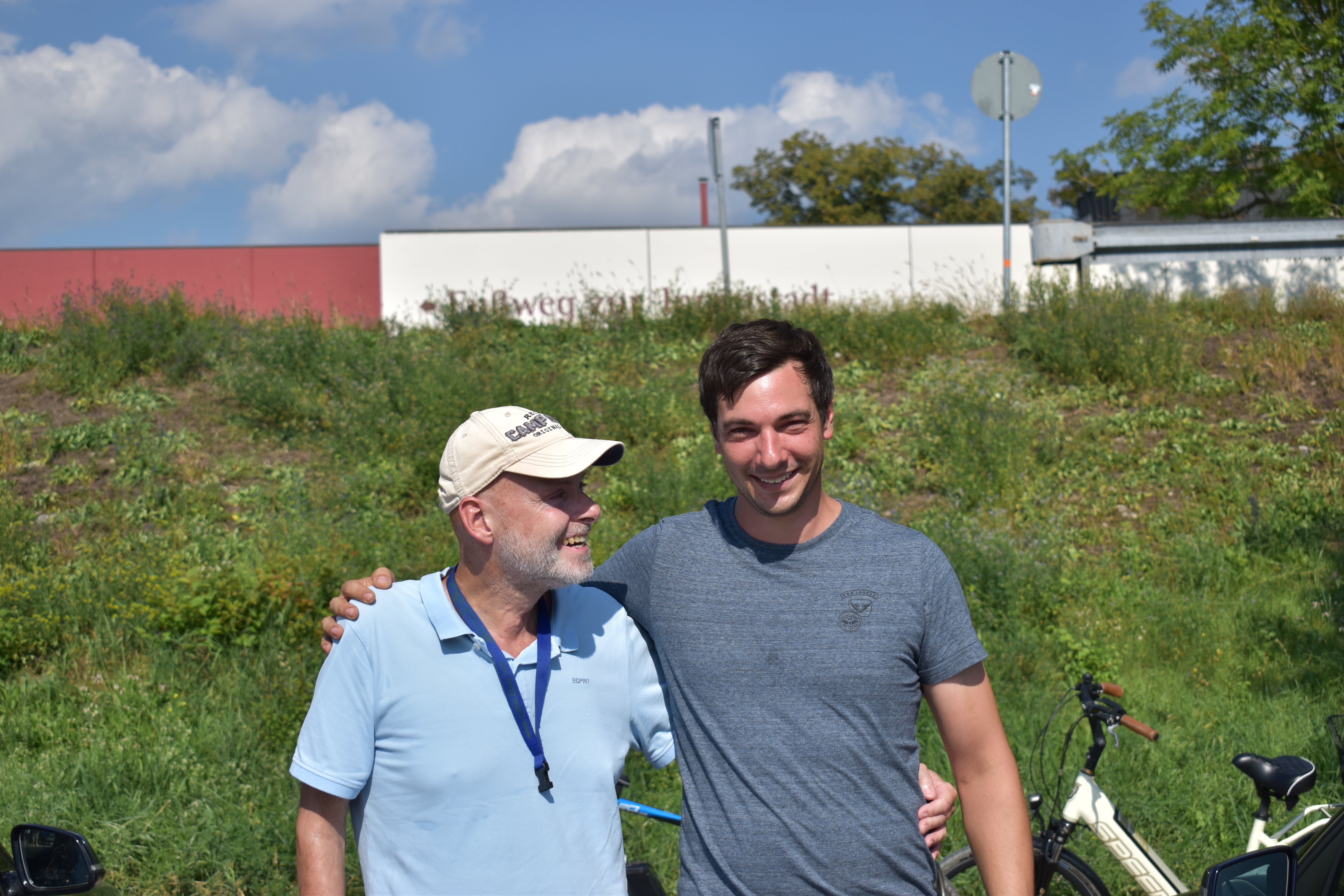Stefan und Michael stehen nebeneinander. Sie legen beide einen Arm um den anderen.