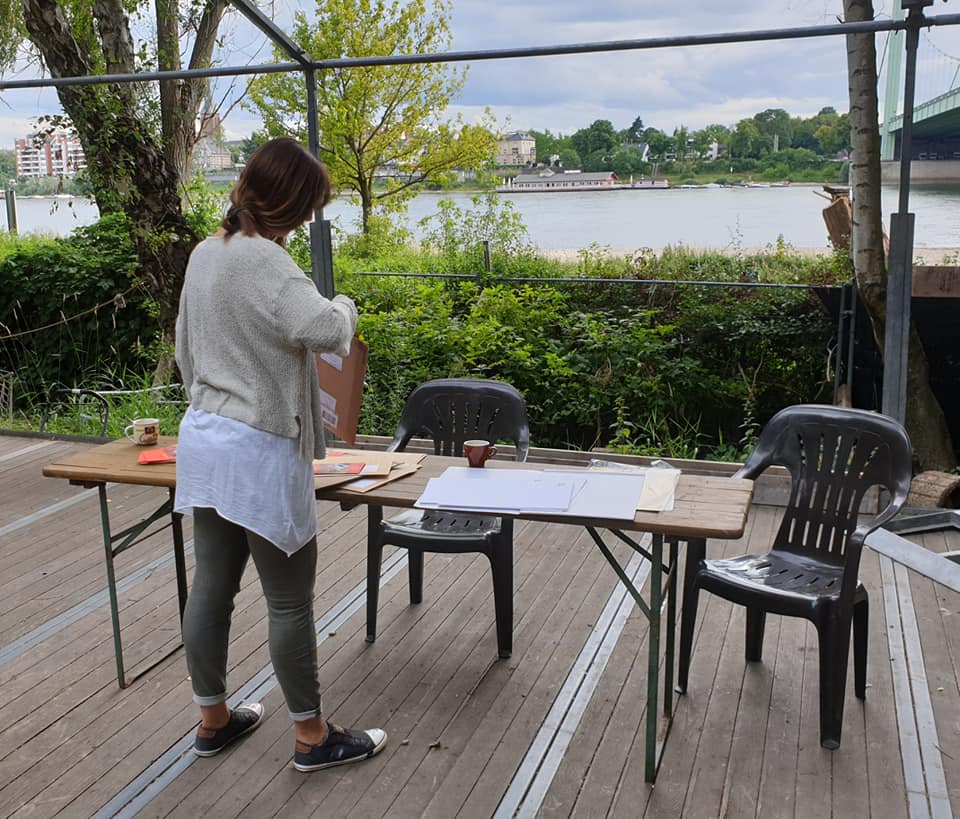 Eine Frau steht draußen auf einer Terrasse mit Tisch und Stühlen