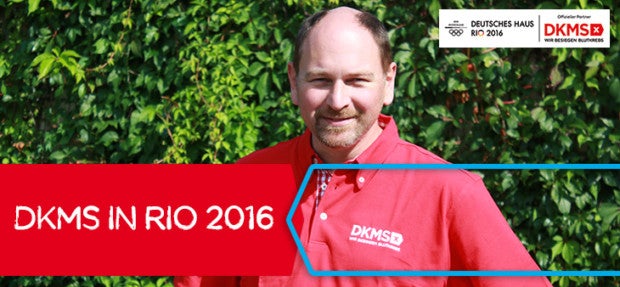 Ein Mann in einem roten Hemd mit DKMS Logo. Auf dem Bild ein rotes Banner mit der Aufschrift DKMS in Rio 2016