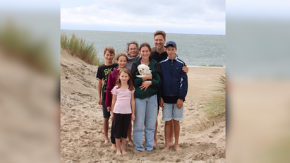 Eine Gruppe von Menschen, die an einem Strand für ein Foto posieren