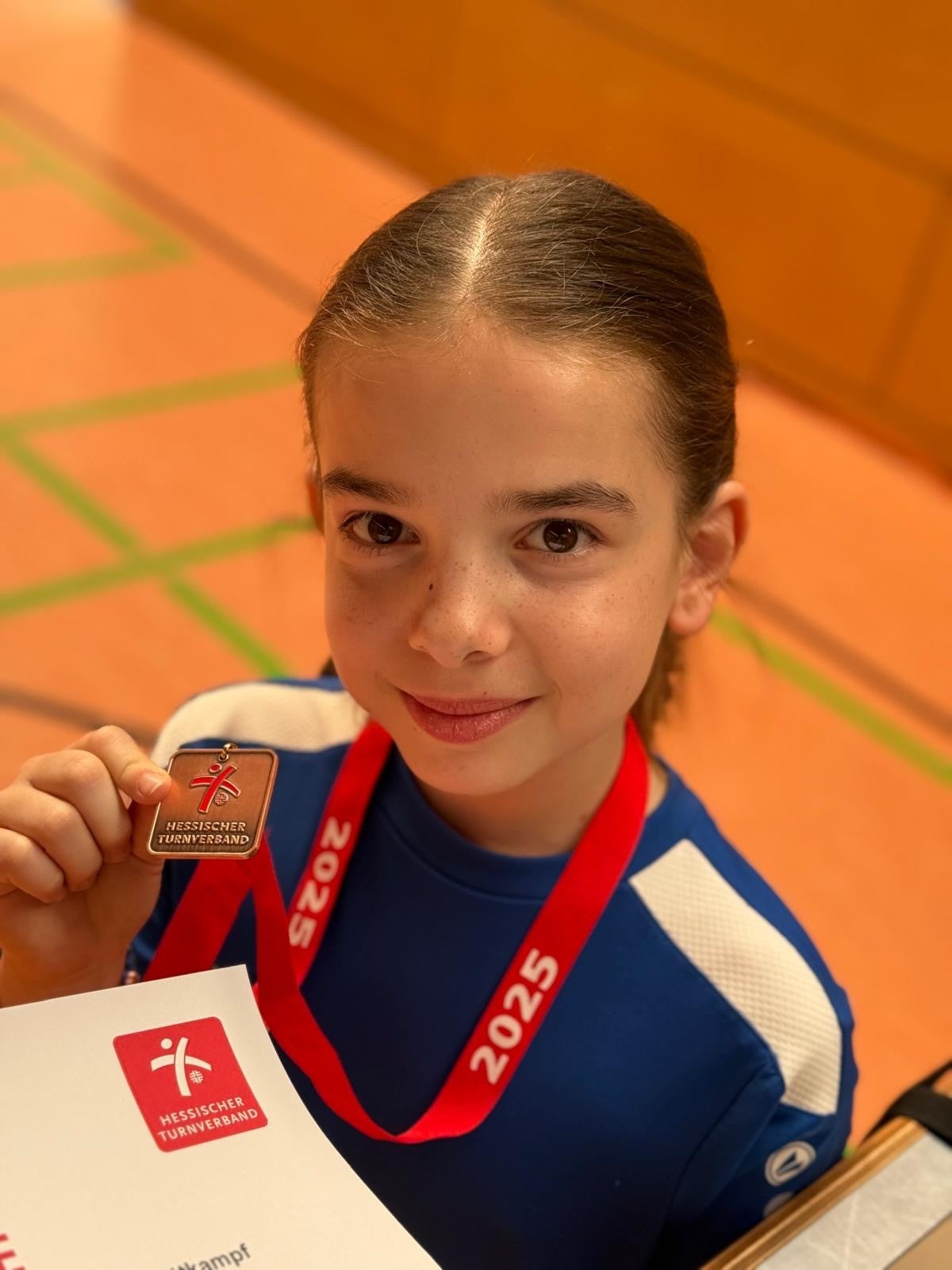 Mila hält eine Medaille