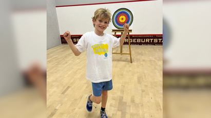 Ein Junge in einem weißen Hemd und blauen Shorts
