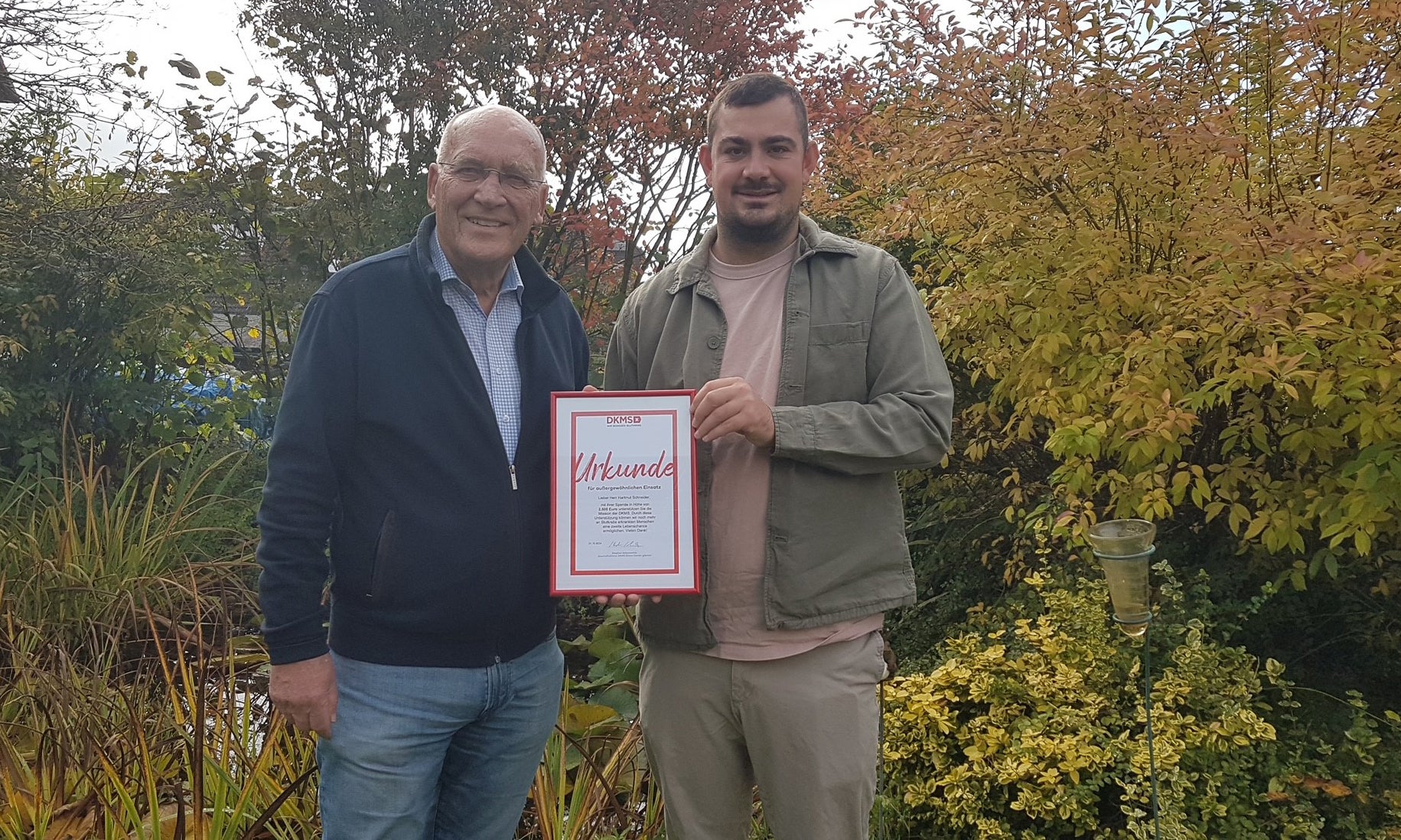 Zwei Männer halten eine Urkunde