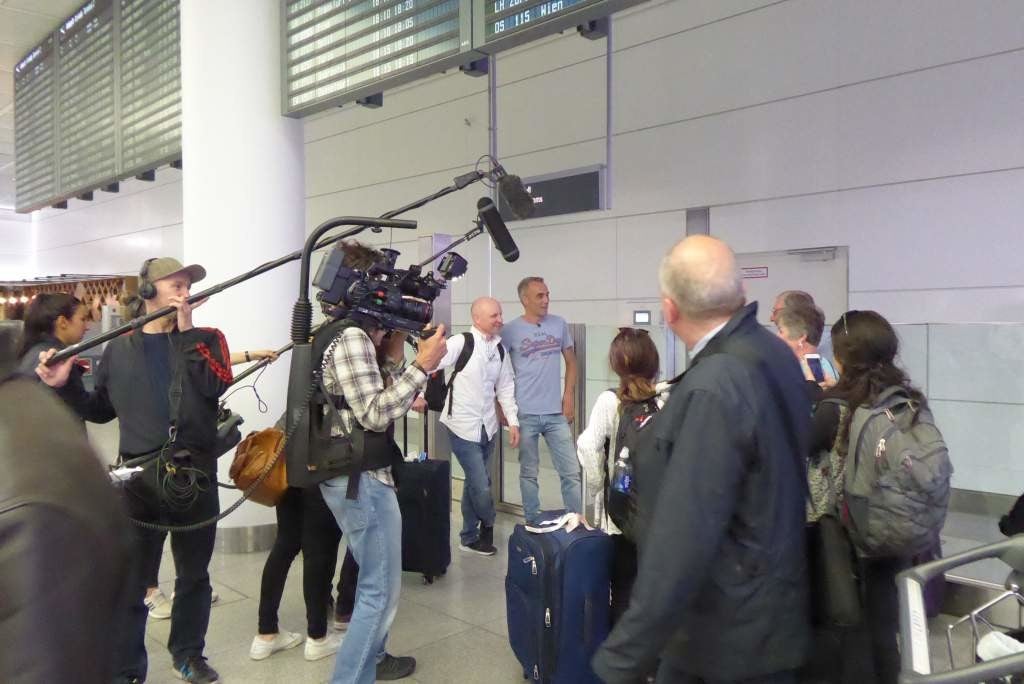 Ein Kamerateam filmt David und Christian an einem Flughafen