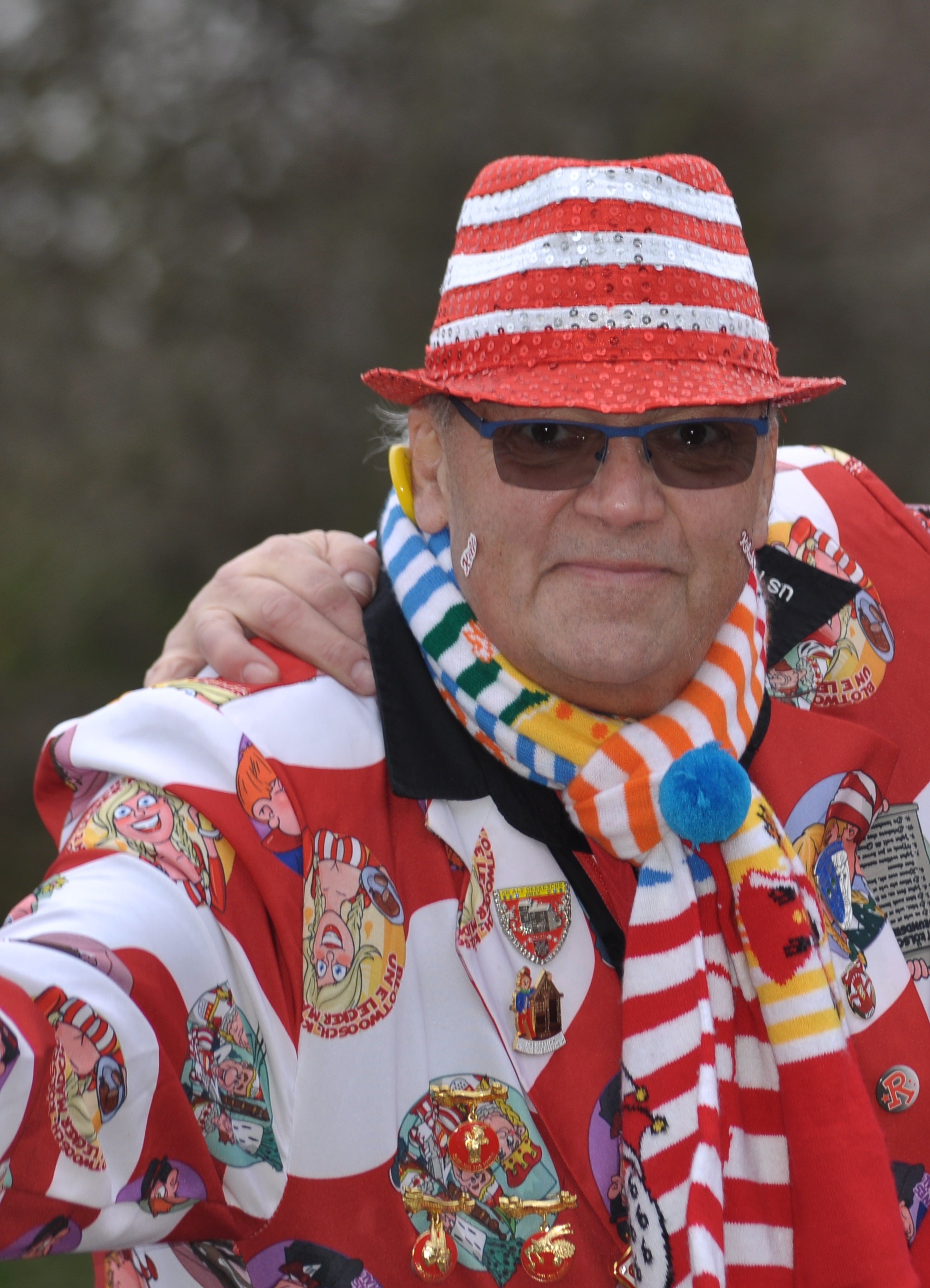 Ein Mann mit einem rot-weiß gestreiften Hut und einer Sonnenbrille posiert für ein Foto