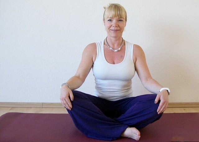 Jeanette im Schneidersitz auf einer Yogamatte