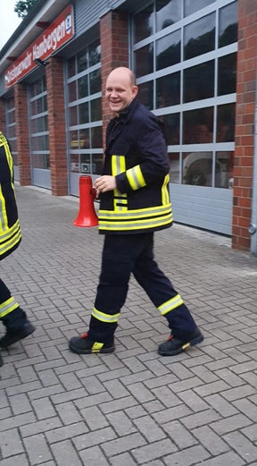 Patient Christian im Feuerwehrmannanzug auf der Wache unterwegs