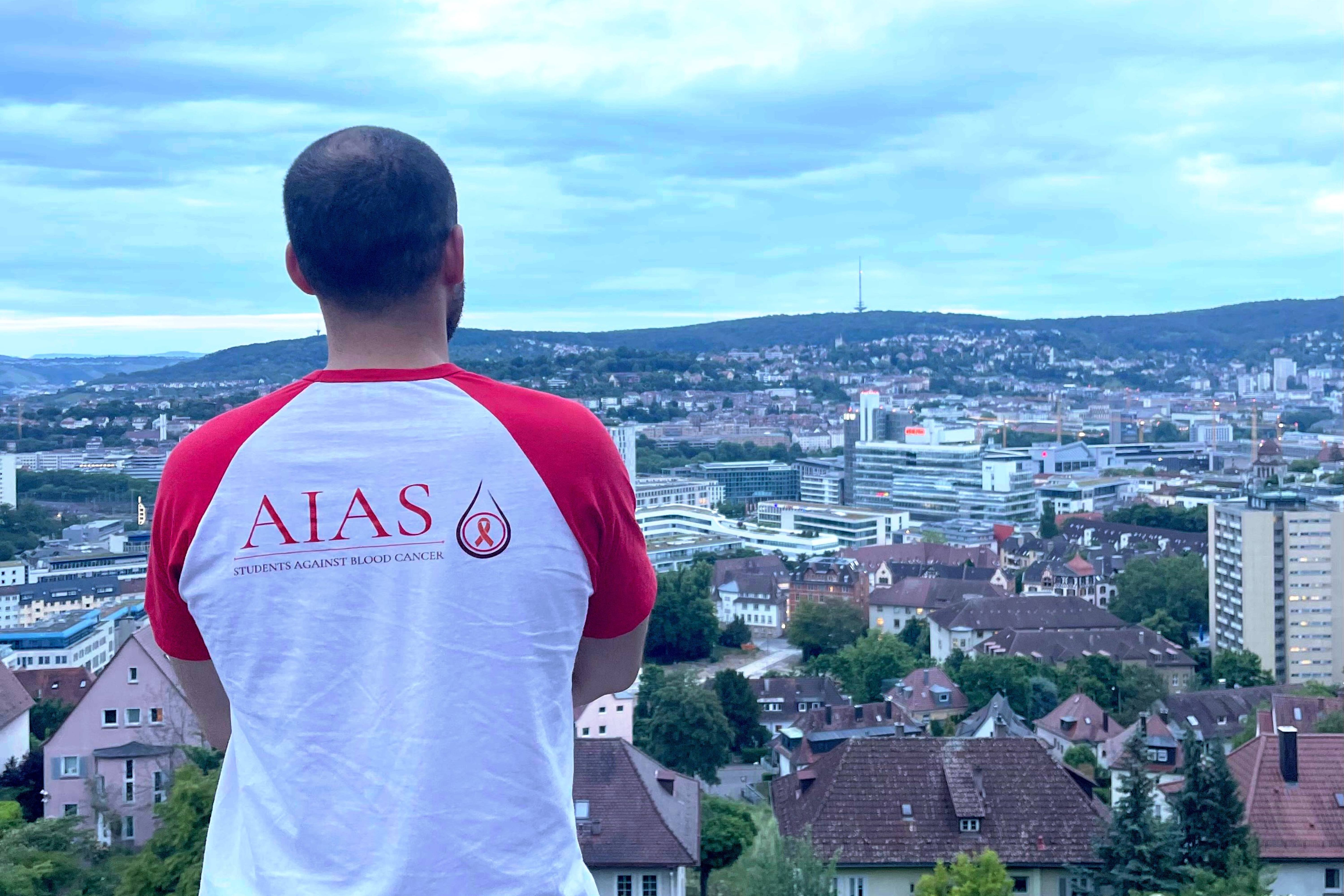 Ein Mann steht auf einem Felsvorsprung und schaut auf eine Stadt