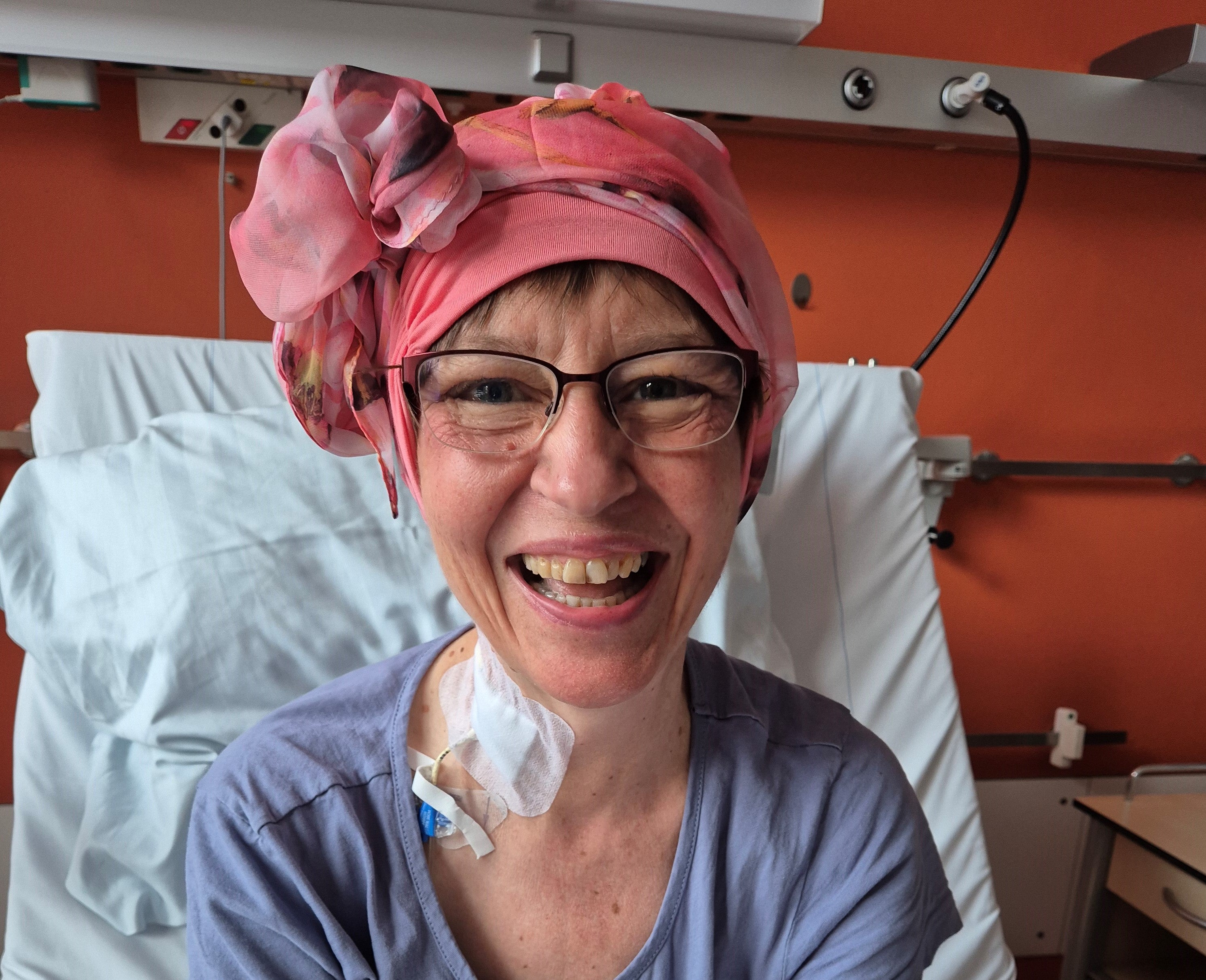 Eine Frau mit rosa Kopfbedeckung lächelt