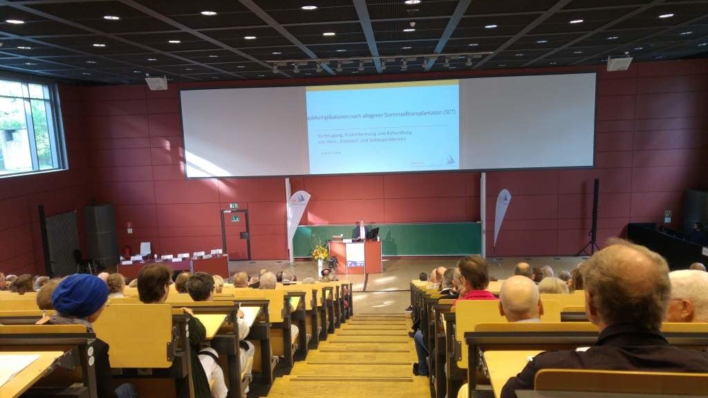 Eine Gruppe von Personen, die in einem Hörsaal mit einer Projektionsfläche sitzen