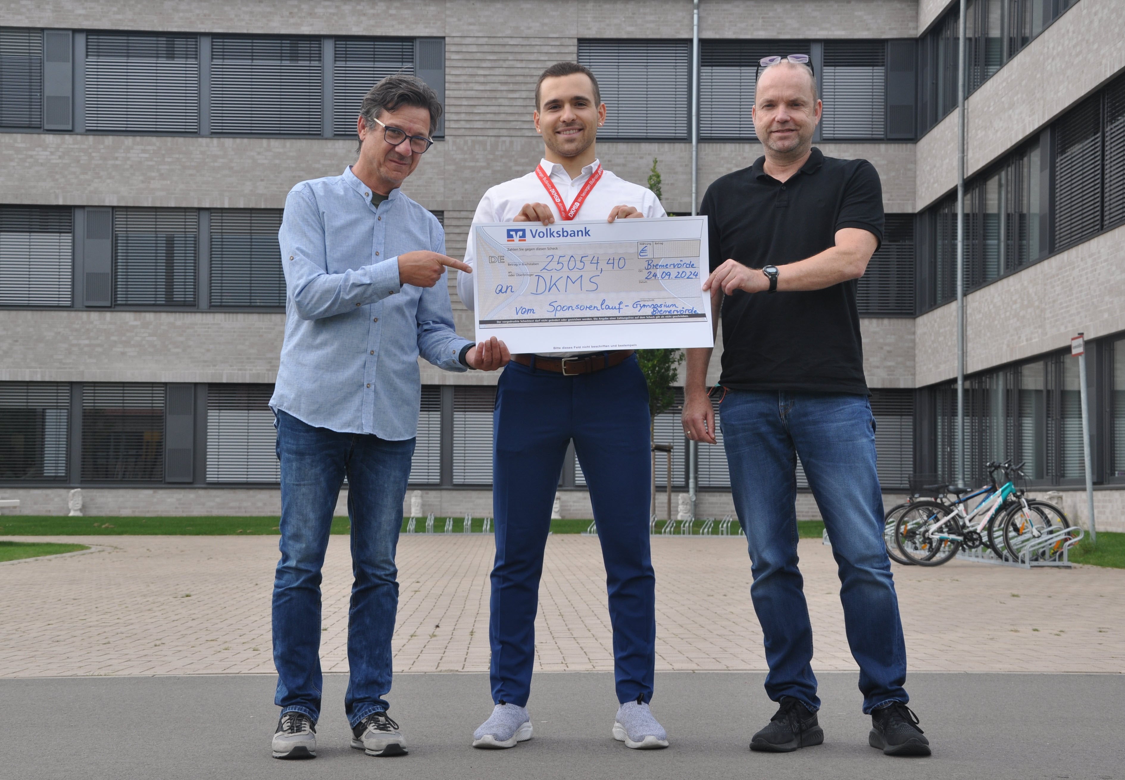 Drei Männer die einen Scheck halten